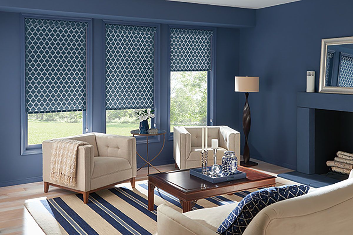 A living room with blue walls , a couch , chairs , a coffee table and a fireplace.