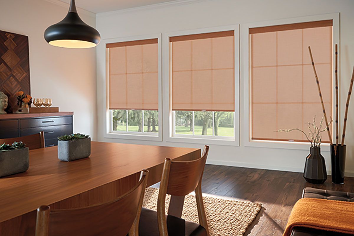 A dining room with a table and chairs and a lot of windows.