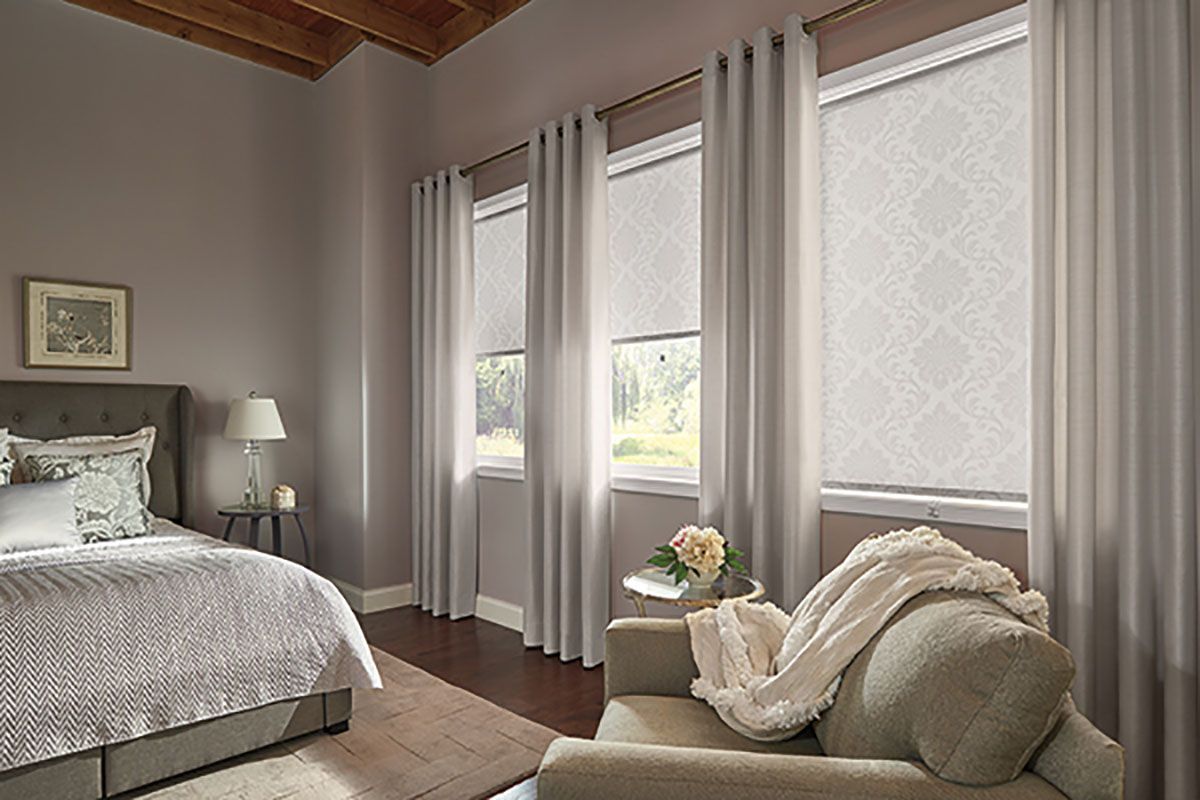A bedroom with a bed , chair , and curtains.