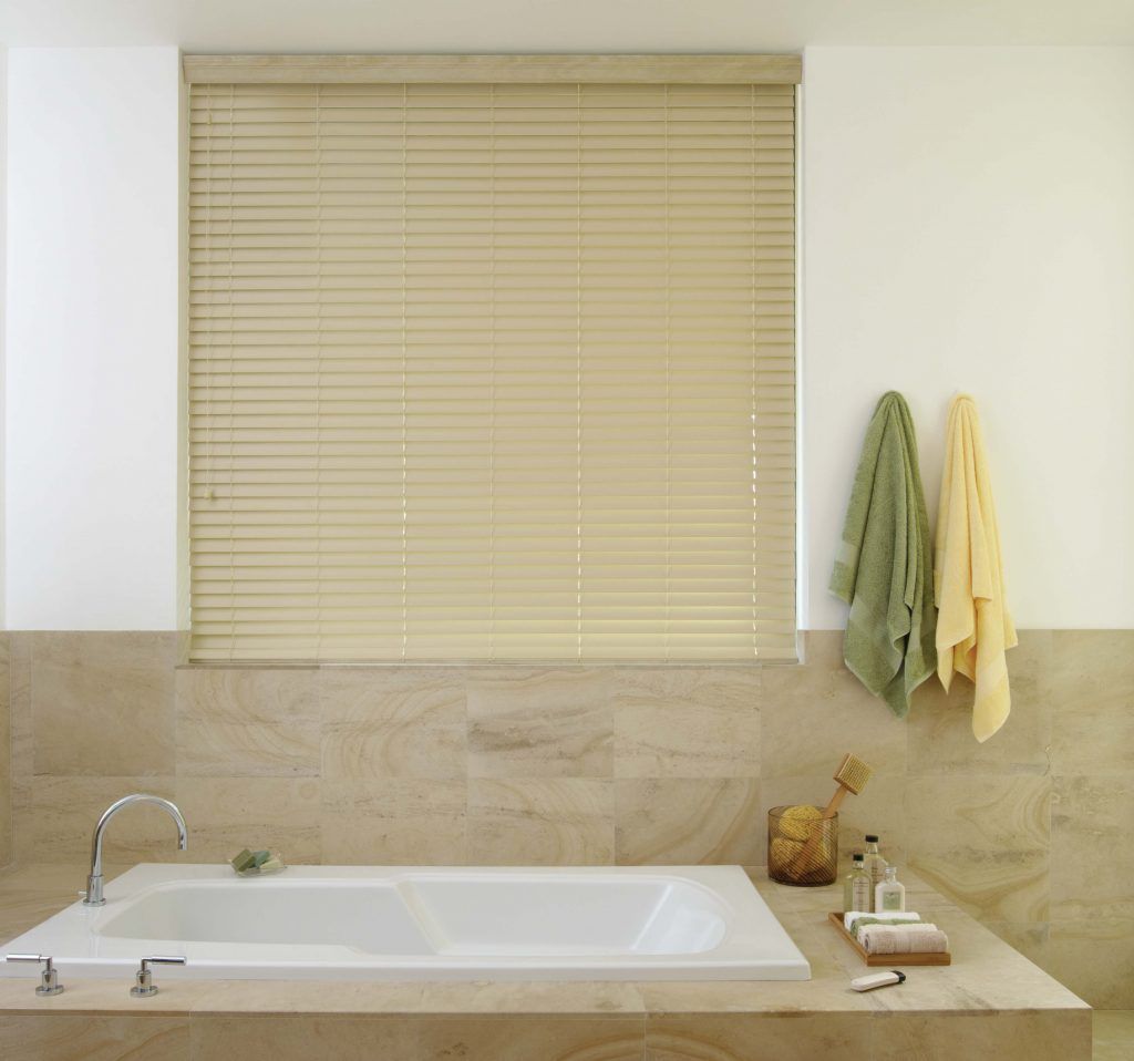 A bathroom with a tub and a window with blinds