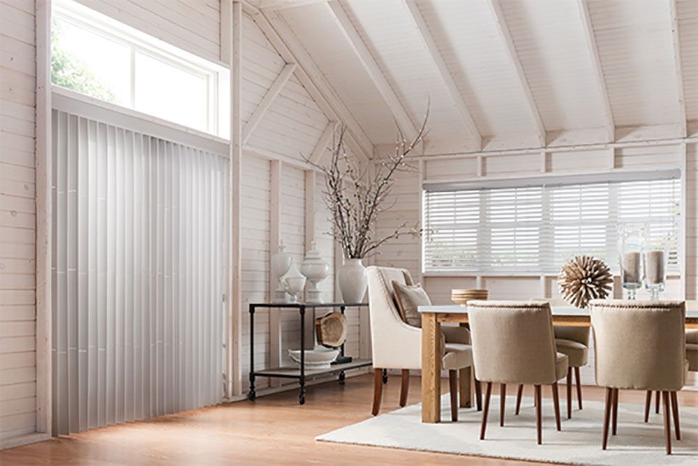 A dining room with a table and chairs and white blinds.