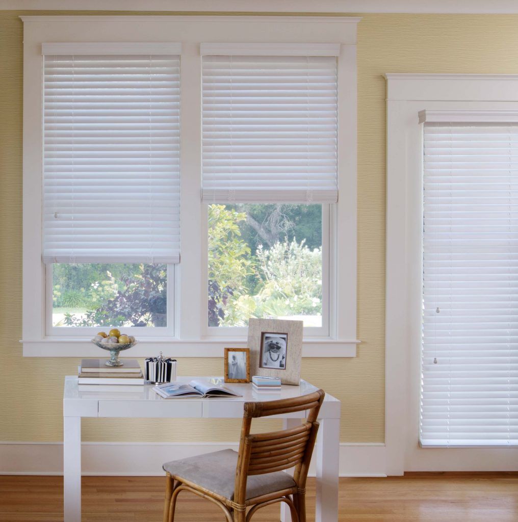 A desk and chair in a room with blinds on the windows