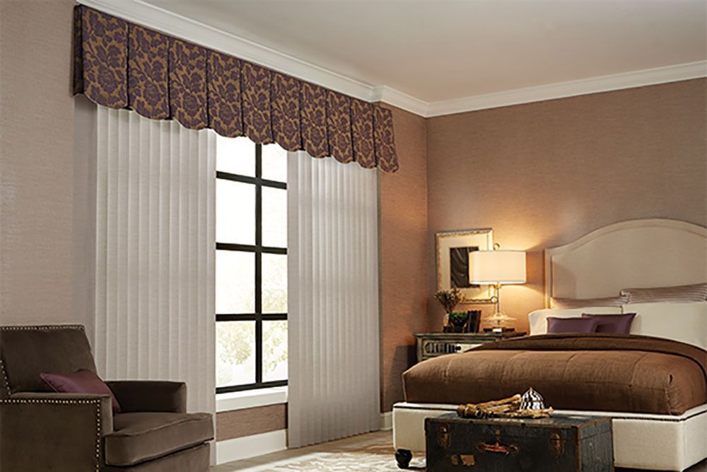 A bedroom with a bed , chair , coffee table and window.