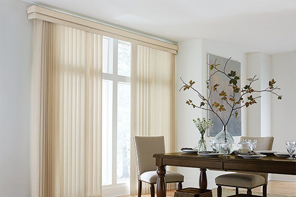 A dining room with a table and chairs and vertical blinds on the windows.