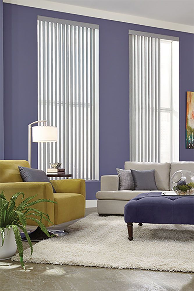 A living room with purple walls and white vertical blinds.