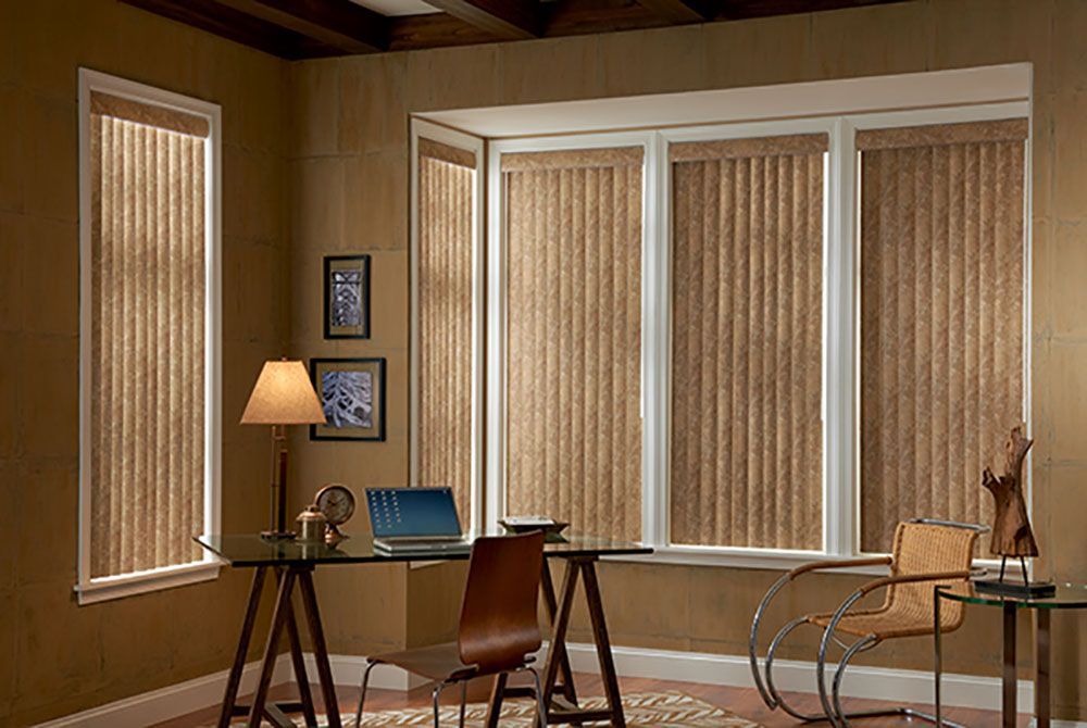 A room with a desk and chairs and a window with blinds