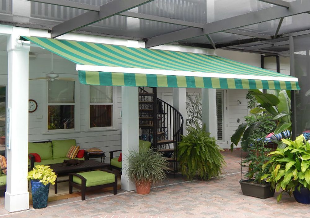A green and white striped awning is hanging over a patio with a spiral staircase.