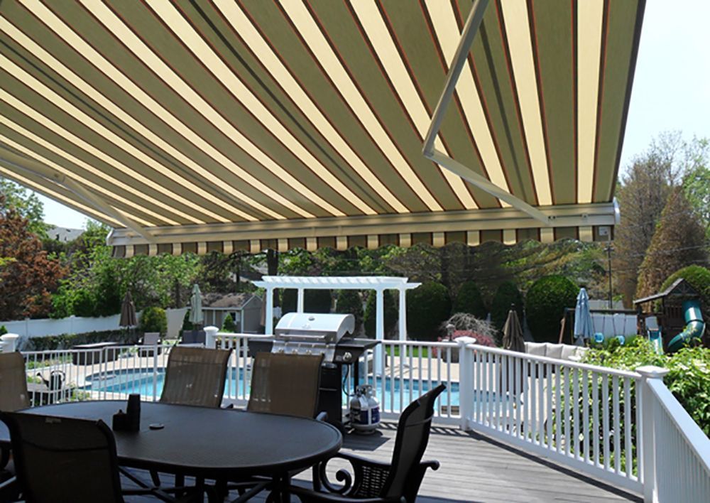 A patio with a table and chairs under an awning overlooking a pool