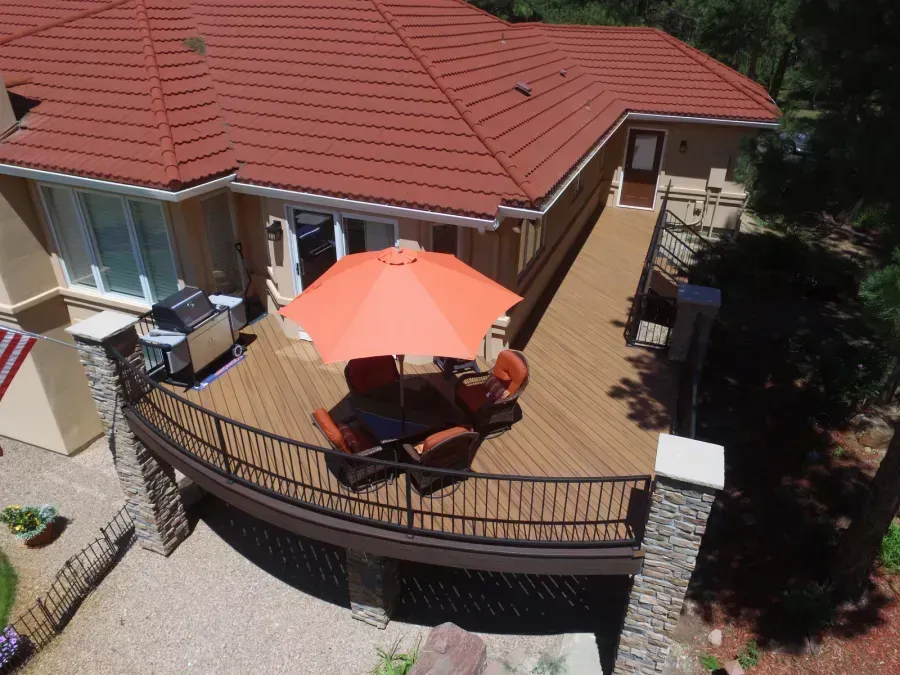 Patio with orange umbrella and outdoor chairs beside a house with a red-tiled roof