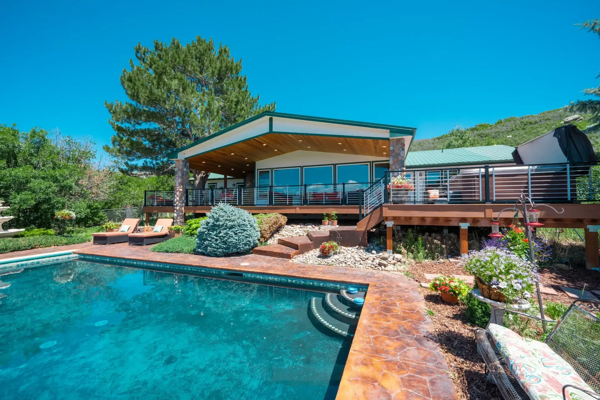 Modern house with a large turquoise swimming pool and landscaped backyard under a clear blue sky
