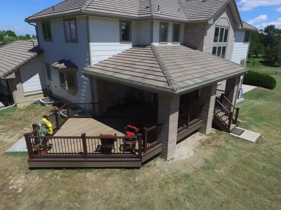 Two-story house with covered porch and fenced deck in a sunny yard