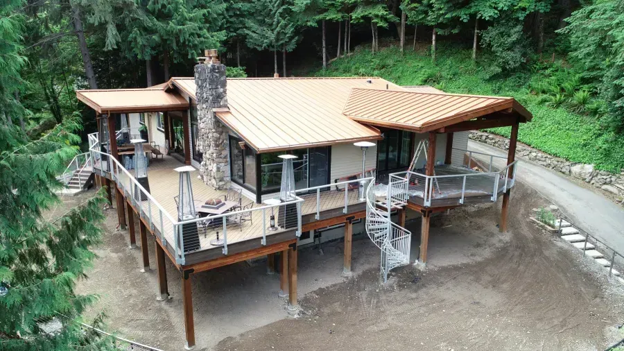 Modern cabin-style house with decks and stairs in a wooded clearing