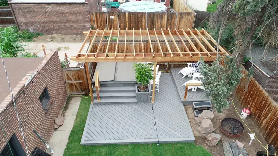 Backyard patio with pergola frame, gray deck, brick walls, and outdoor seating area