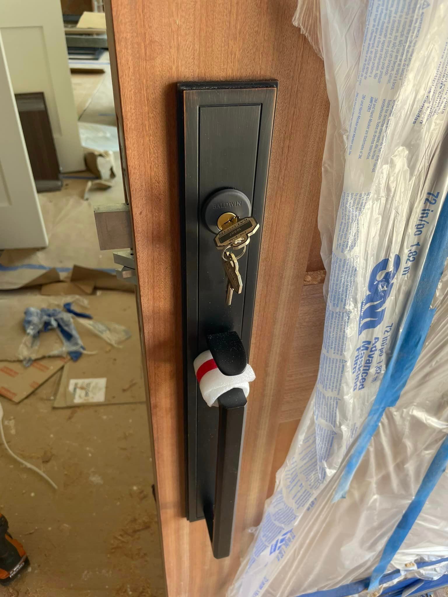 Black door handle and lock with keys on a wood door, construction site.