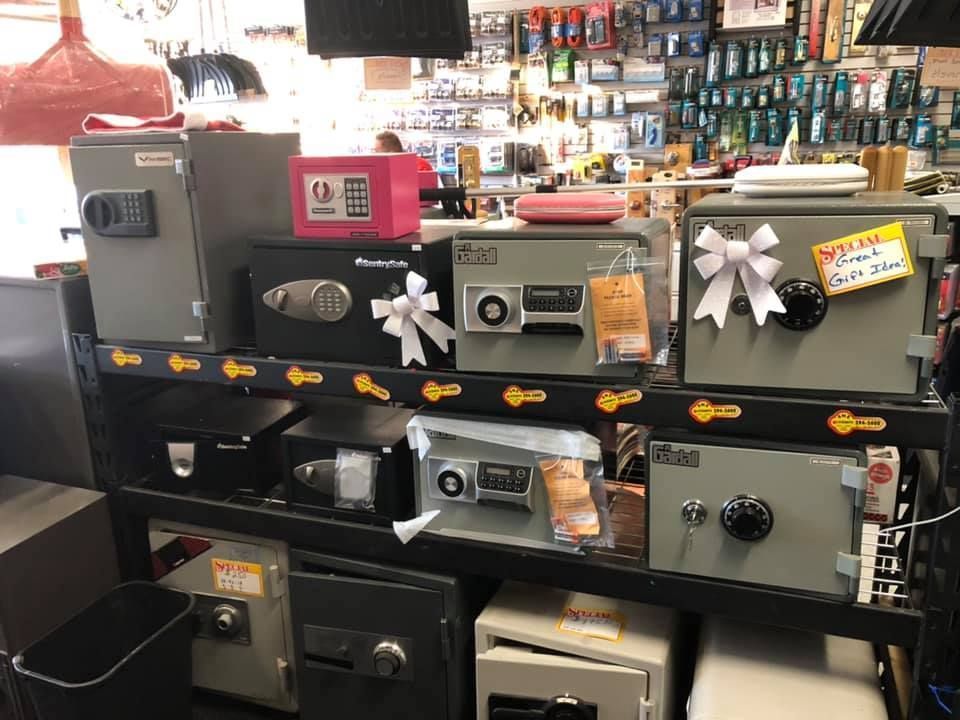 Shelves displaying various safes in a store; some are decorated with bows, surrounded by other merchandise.