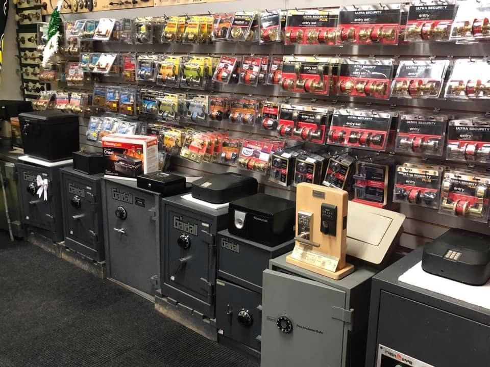 A store interior displays safes of various sizes, with a wall of packaged locks in the background.