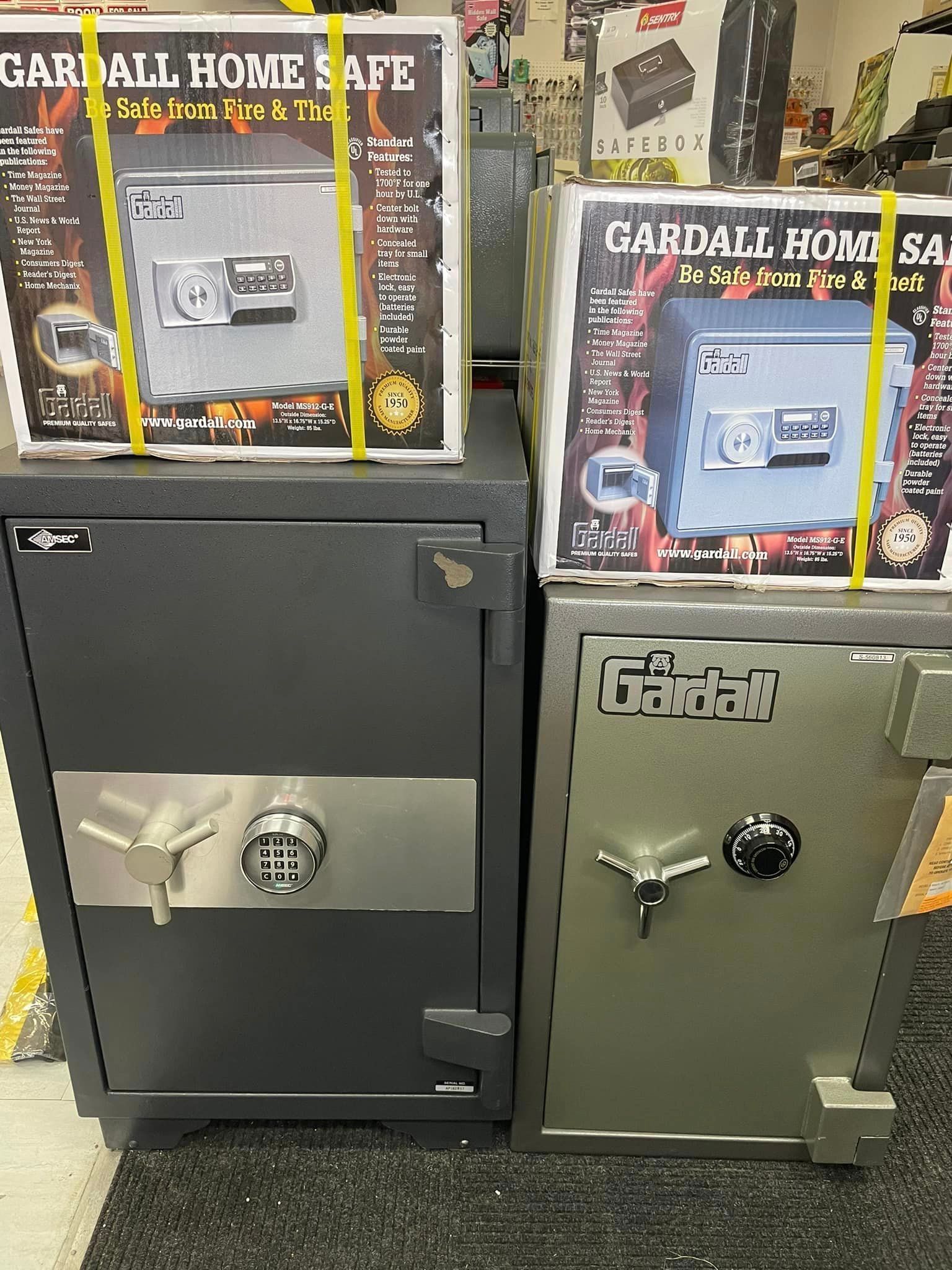 Two safes: dark gray and olive, with boxes of Gardall Home Safes on top.