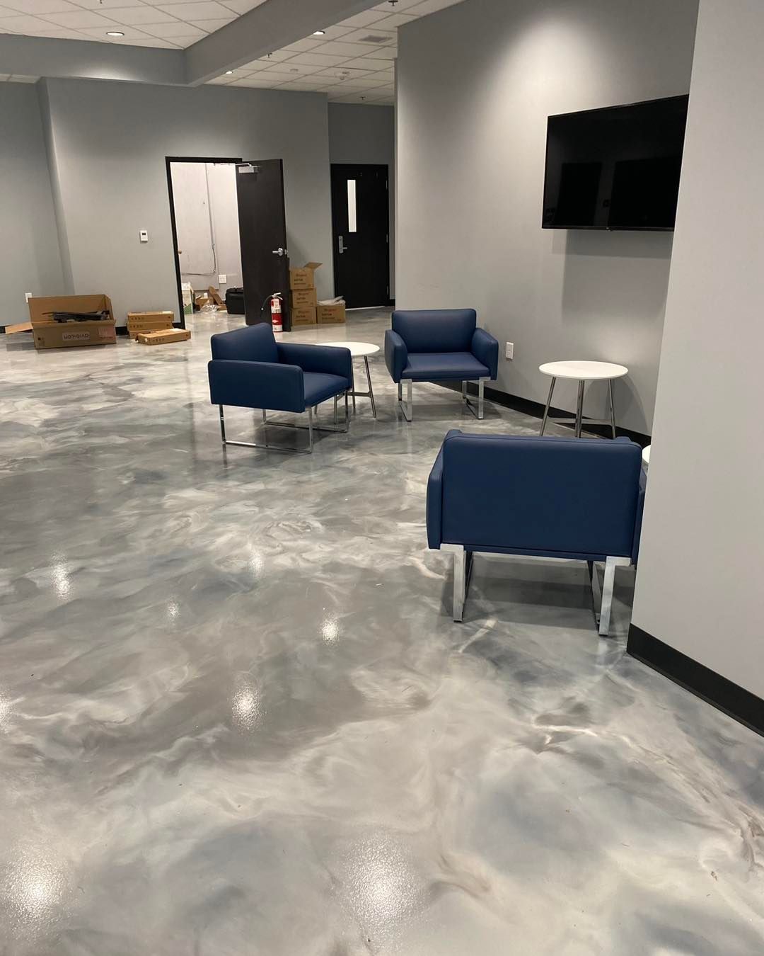 Dark blue, abstract art piece on speckled gray garage floor. White splatter nearby. Car wheel visible.