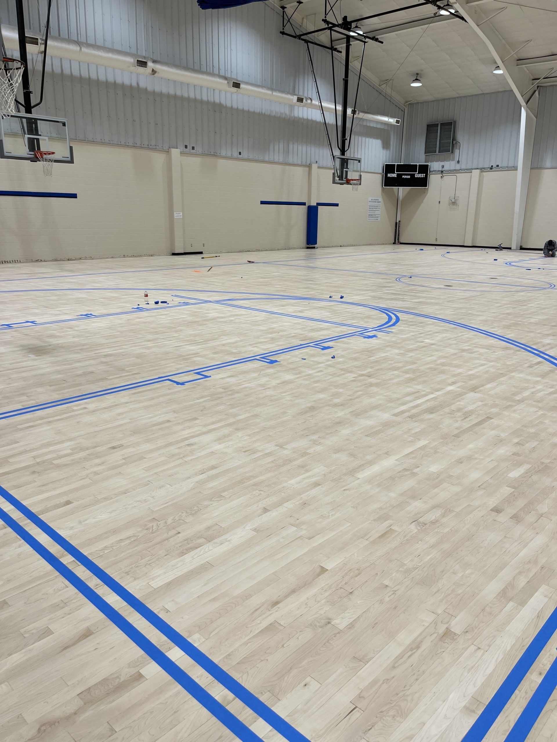Basketball court with blue lines, empty. Baskets mounted. White walls and ceiling.