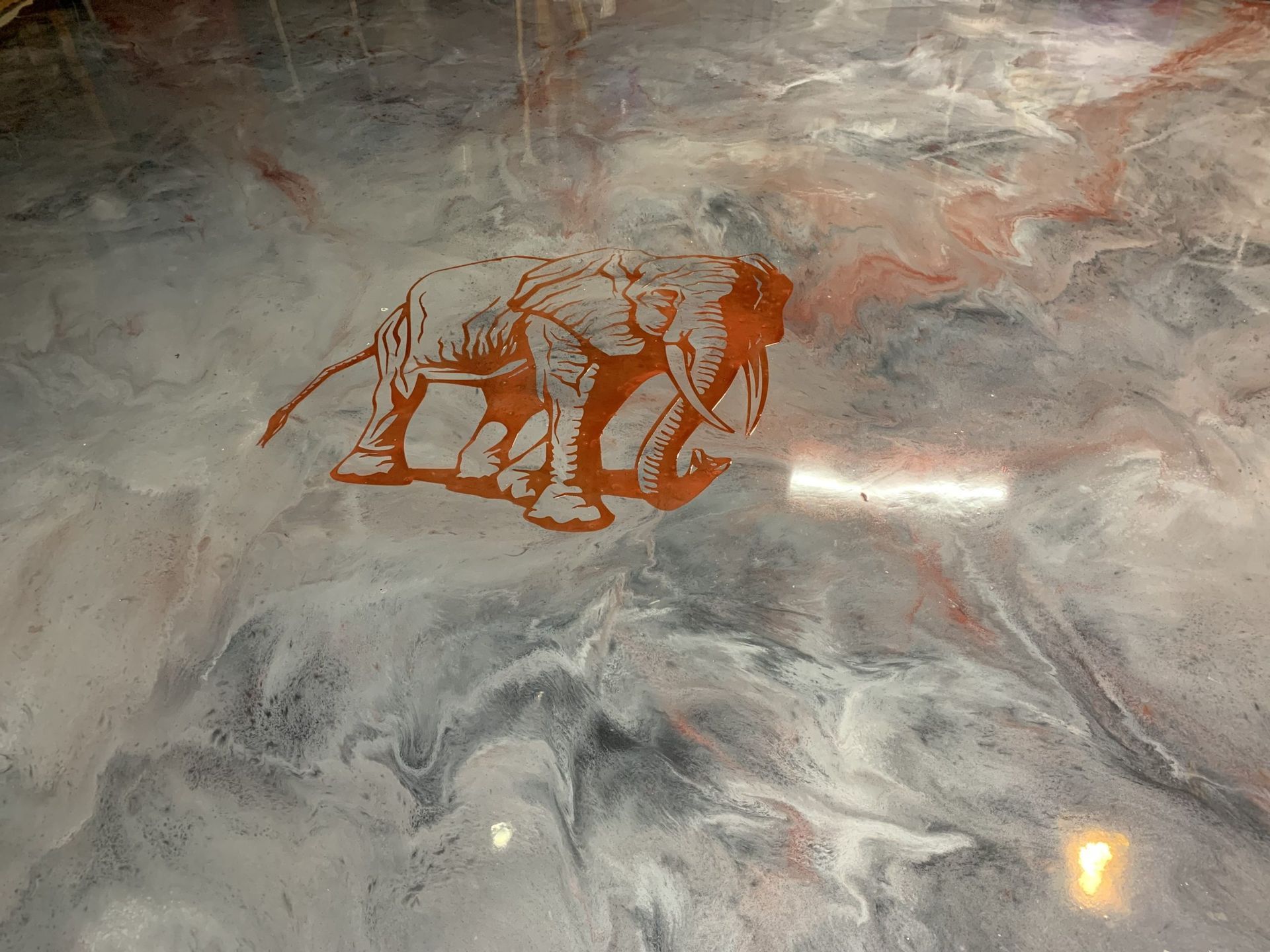 Metallic epoxy floor with elephant silhouette design, white, gray, and copper swirls.