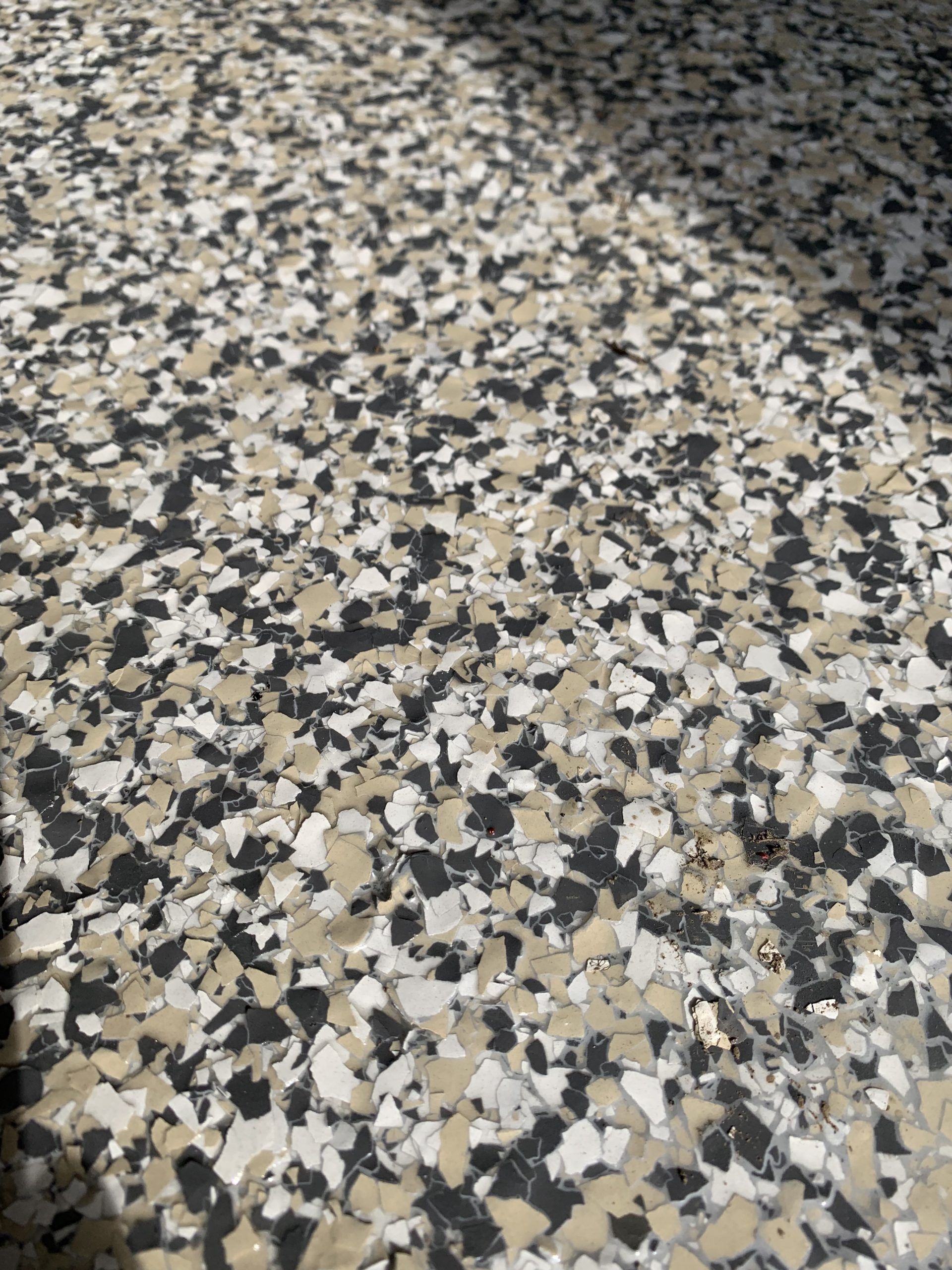 Multi-colored speckled flooring, with black, gray, and cream-colored chips visible.