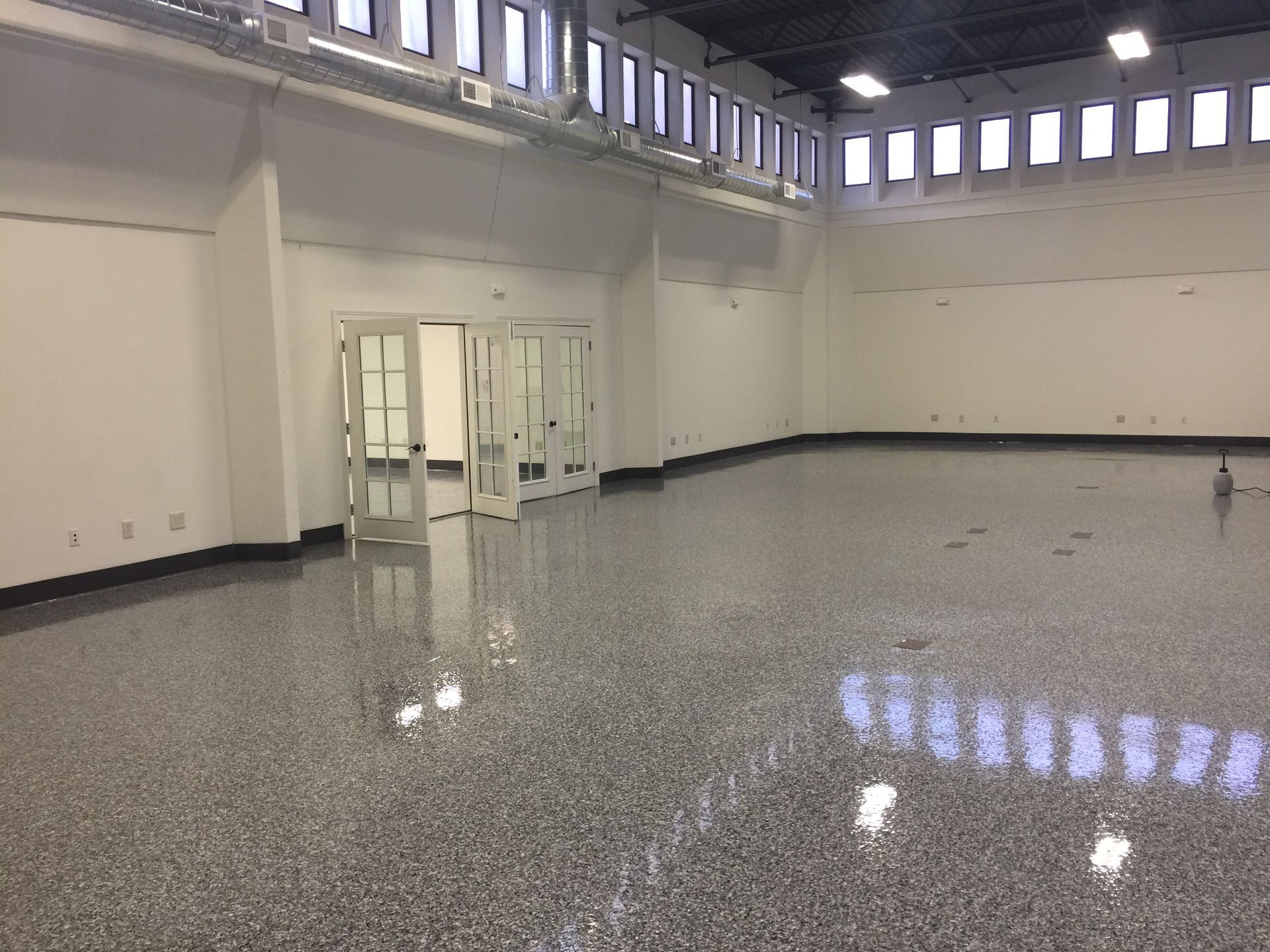 Red and white striped walkway in a warehouse, leading towards white sacks and safety barriers.
