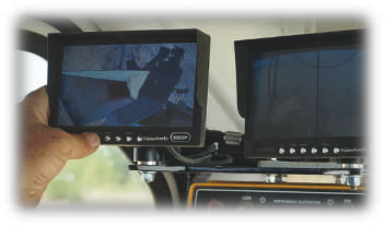 A person is holding a monitor in front of two other monitors