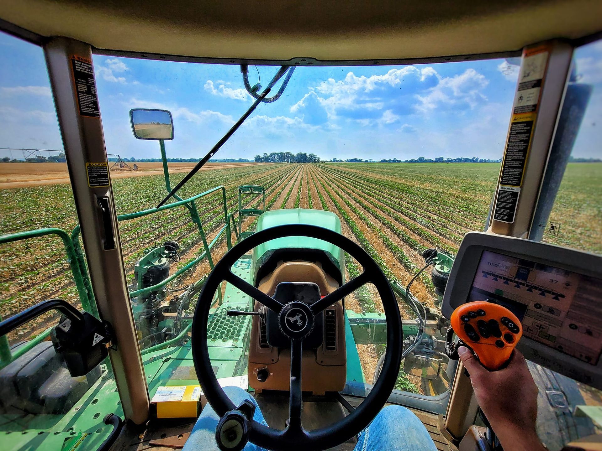 A person is driving a green tractor in a field.