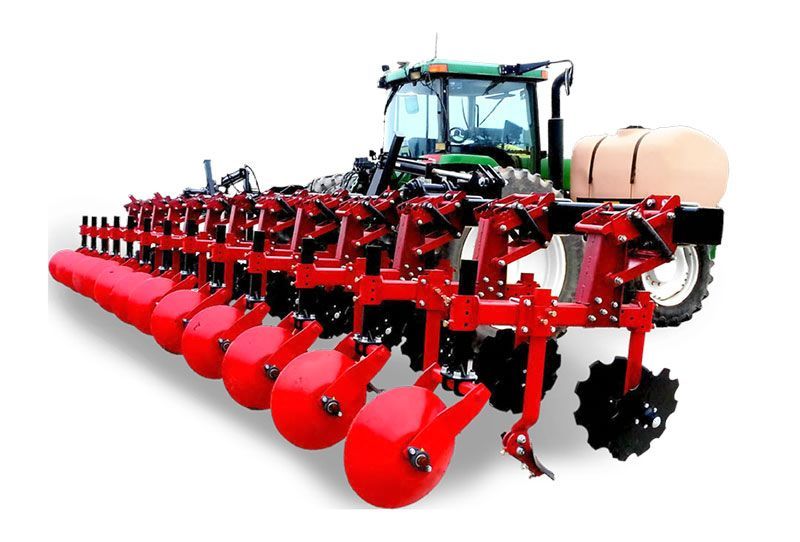 A green tractor with a red plow attached to it