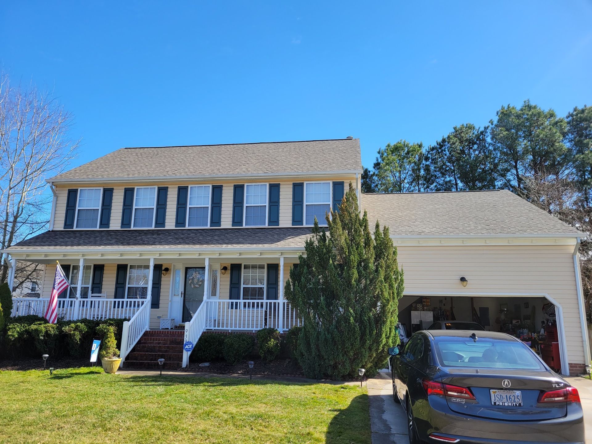 A brick house with a gray roof and a dog in the backyard.