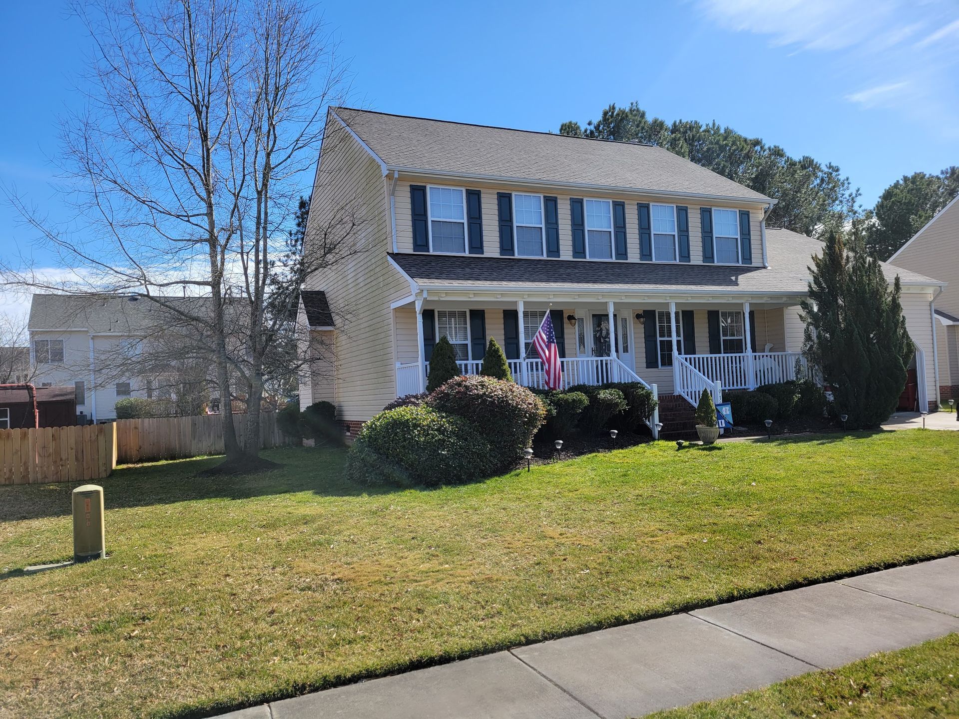 A large house with a large porch is sitting on top of a lush green lawn.