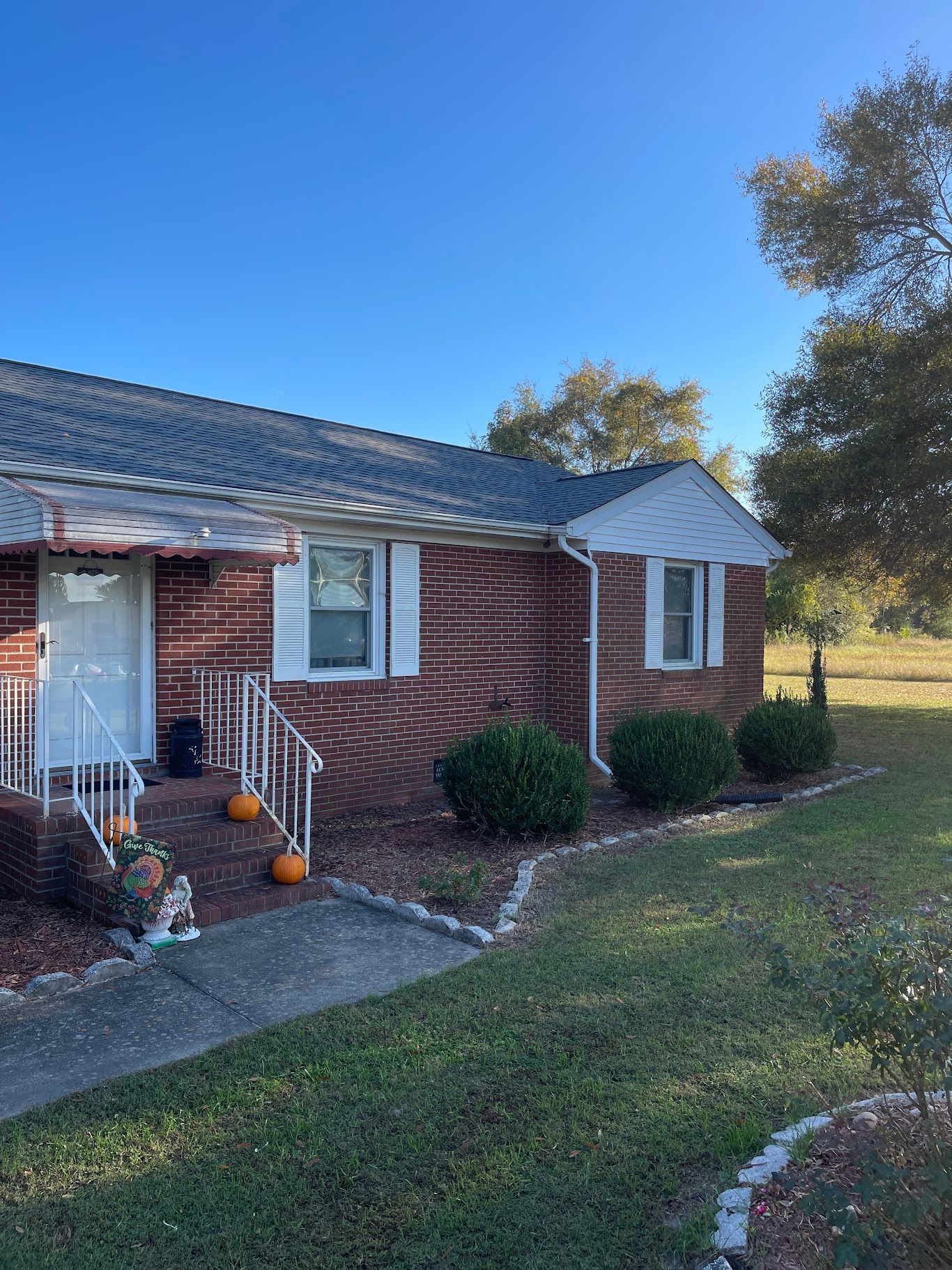 A brick house with pumpkins in front of it on a sunny day.