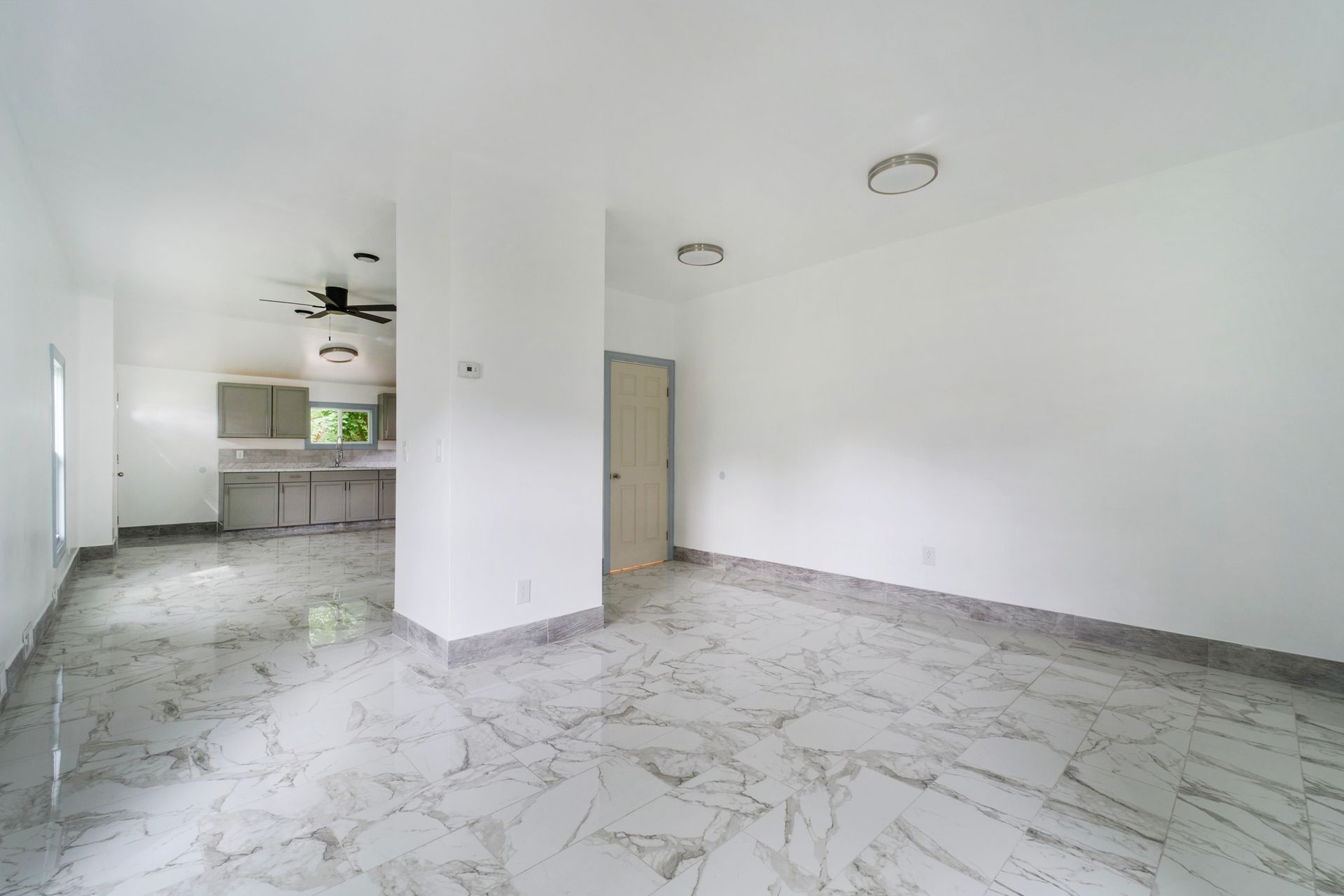 There is a ceiling fan in the living room and a marble floor.