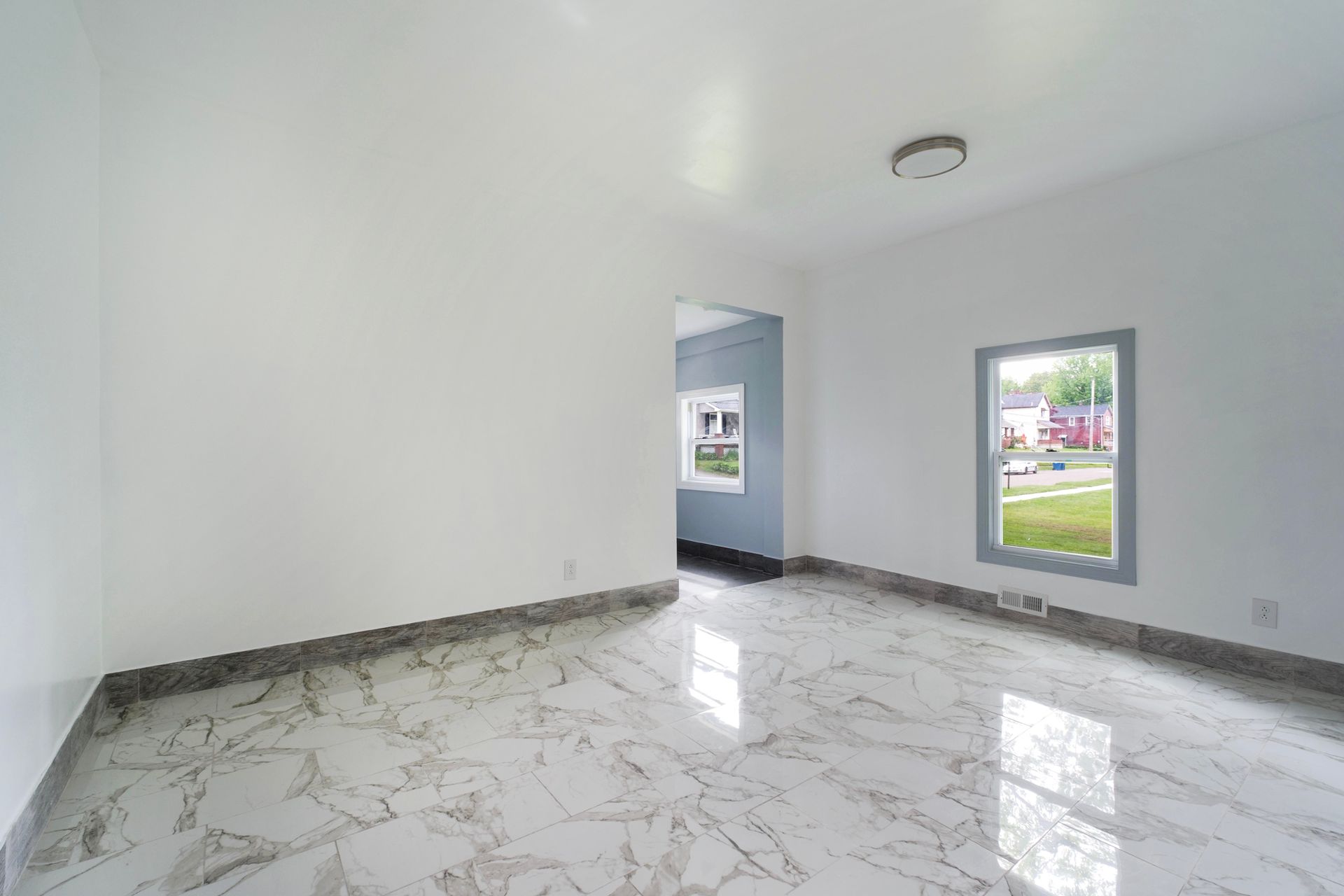 An empty living room with marble floors and white walls.