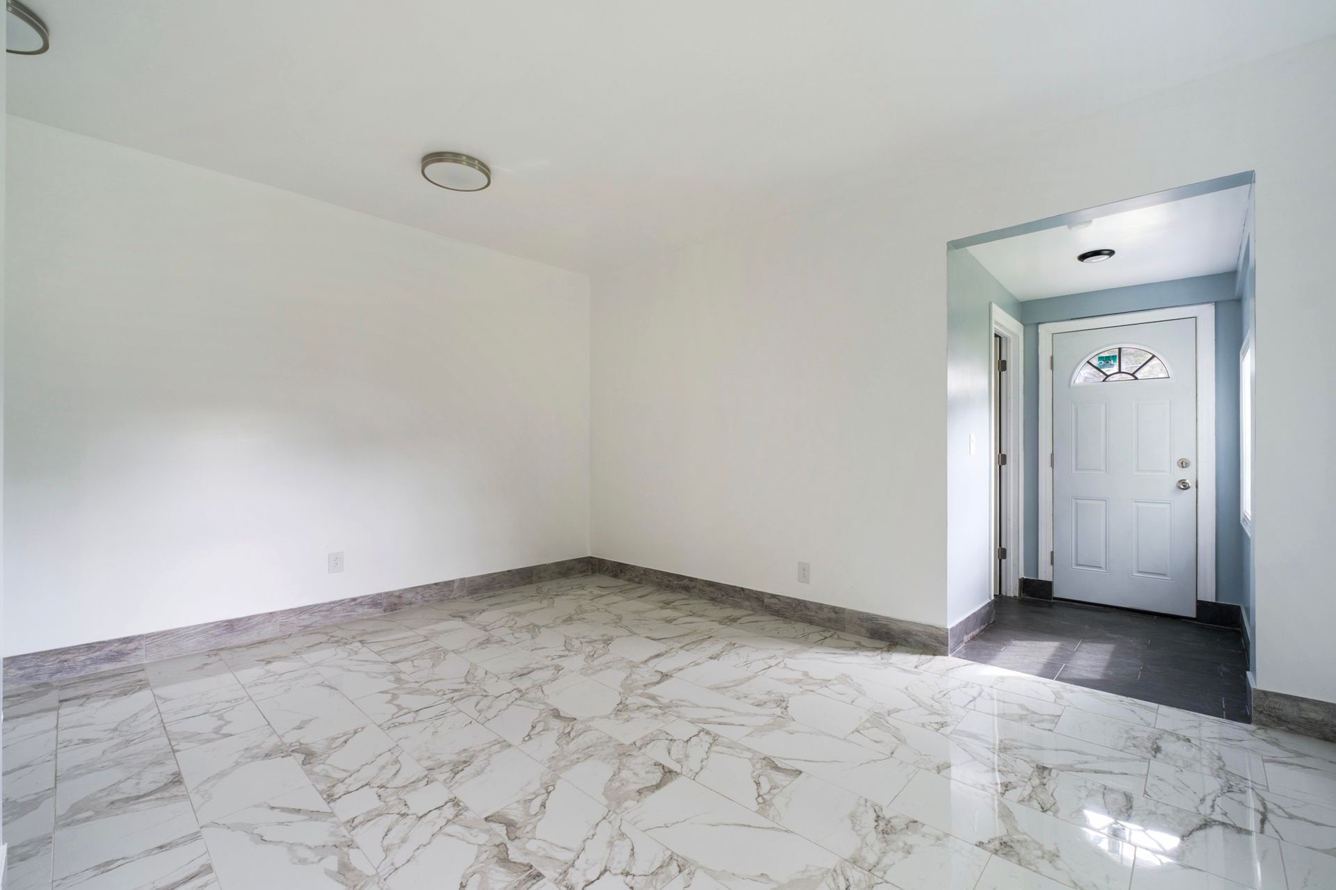 An empty living room with a marble floor and a door.