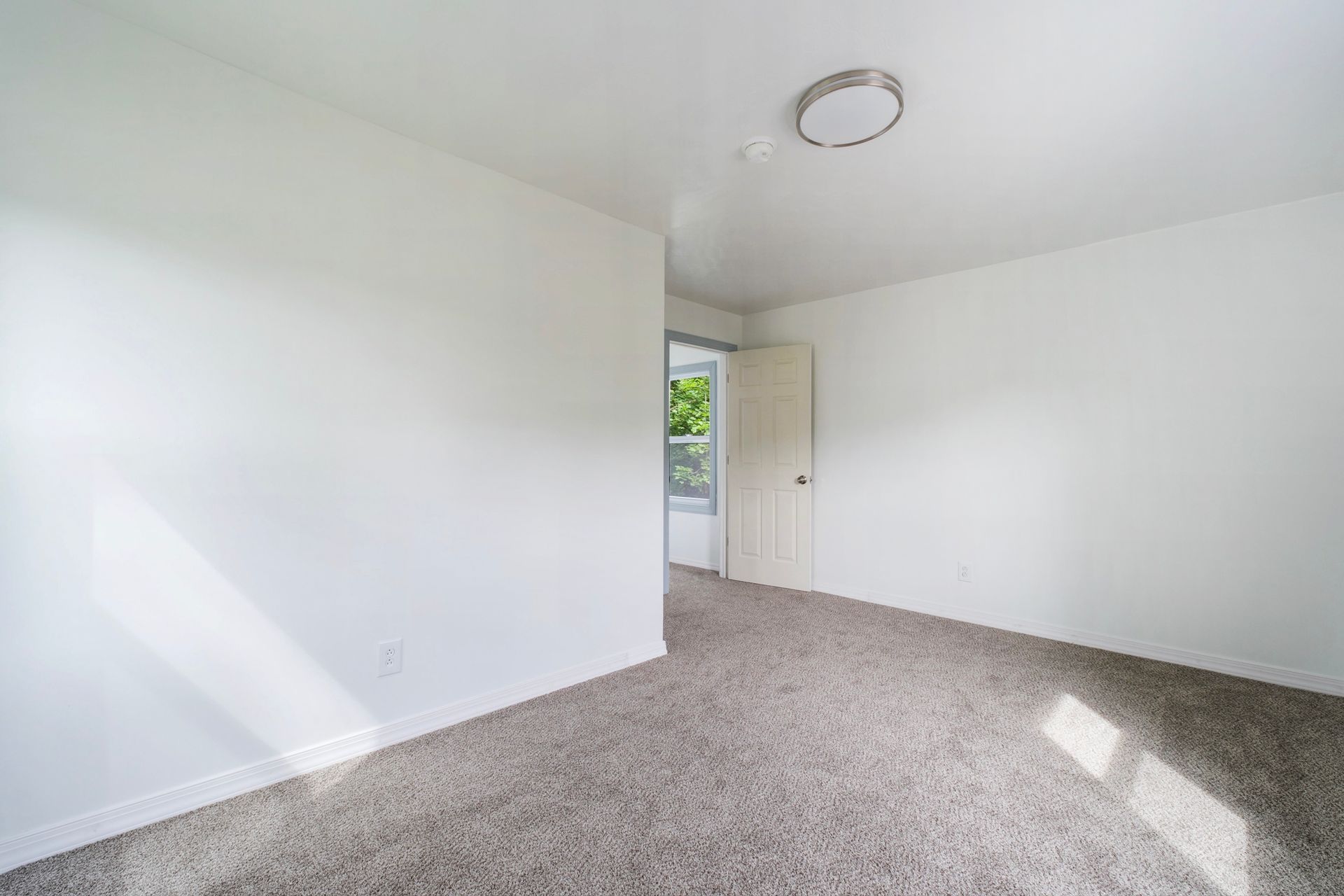 An empty bedroom with a carpeted floor and white walls.