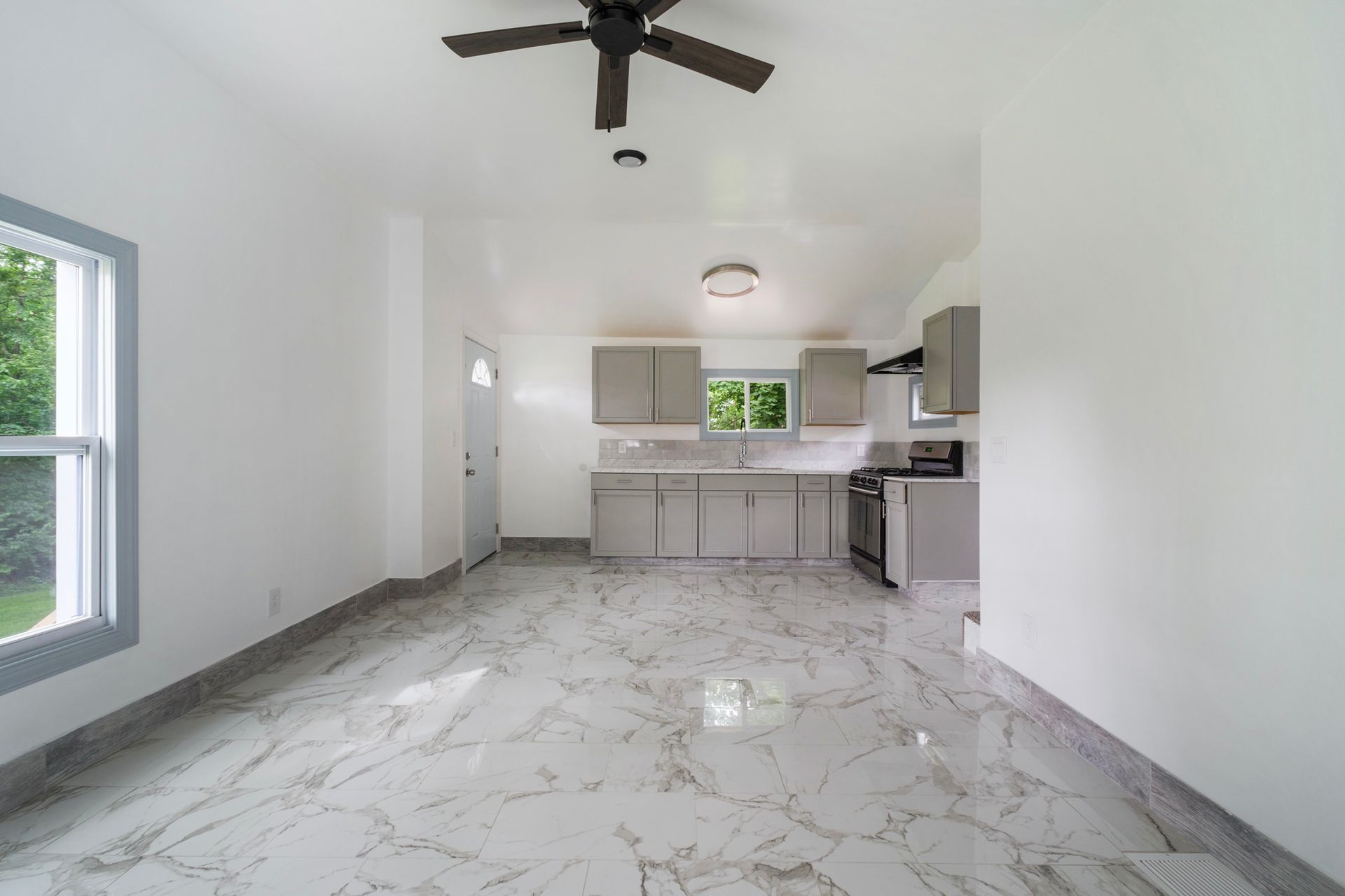 An empty room with a kitchen and a ceiling fan.