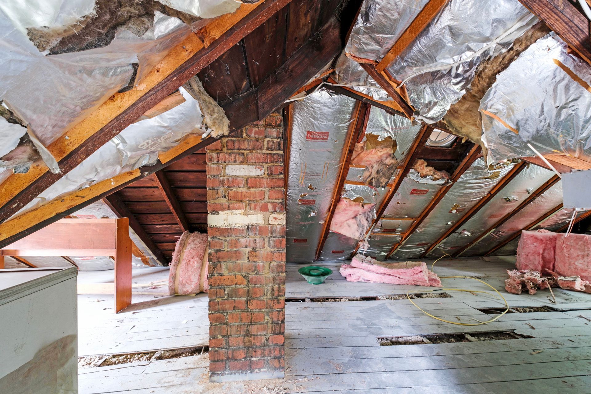 An attic with a brick chimney and a lot of insulation.