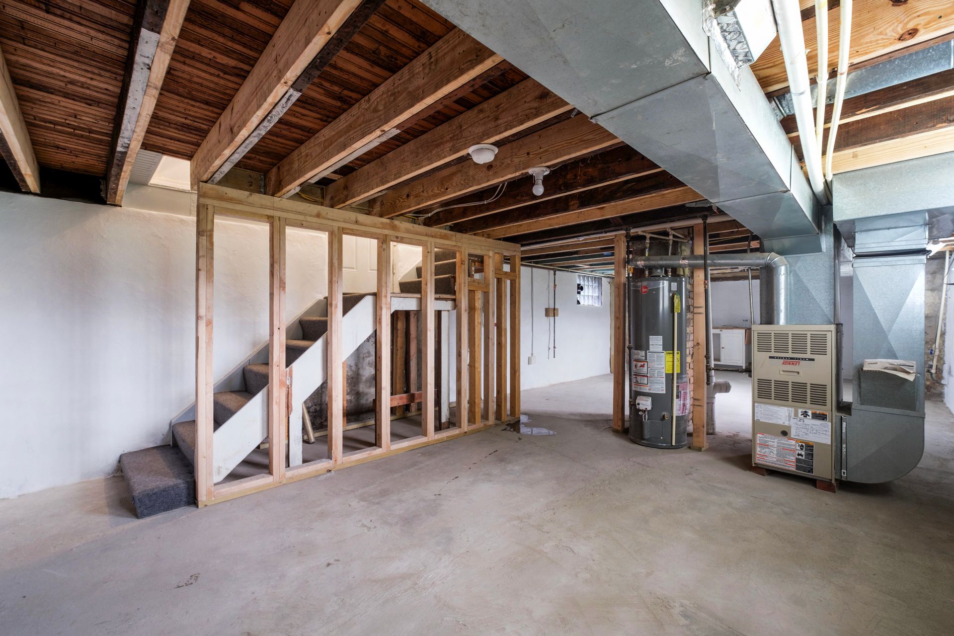 A basement under construction with stairs and a furnace.
