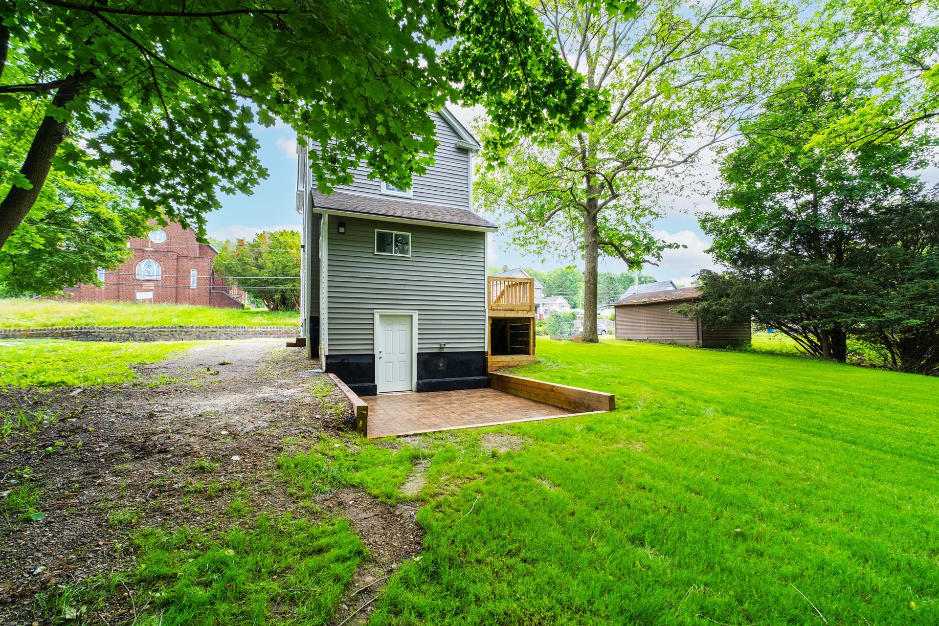 A small house is sitting in the middle of a lush green field.
