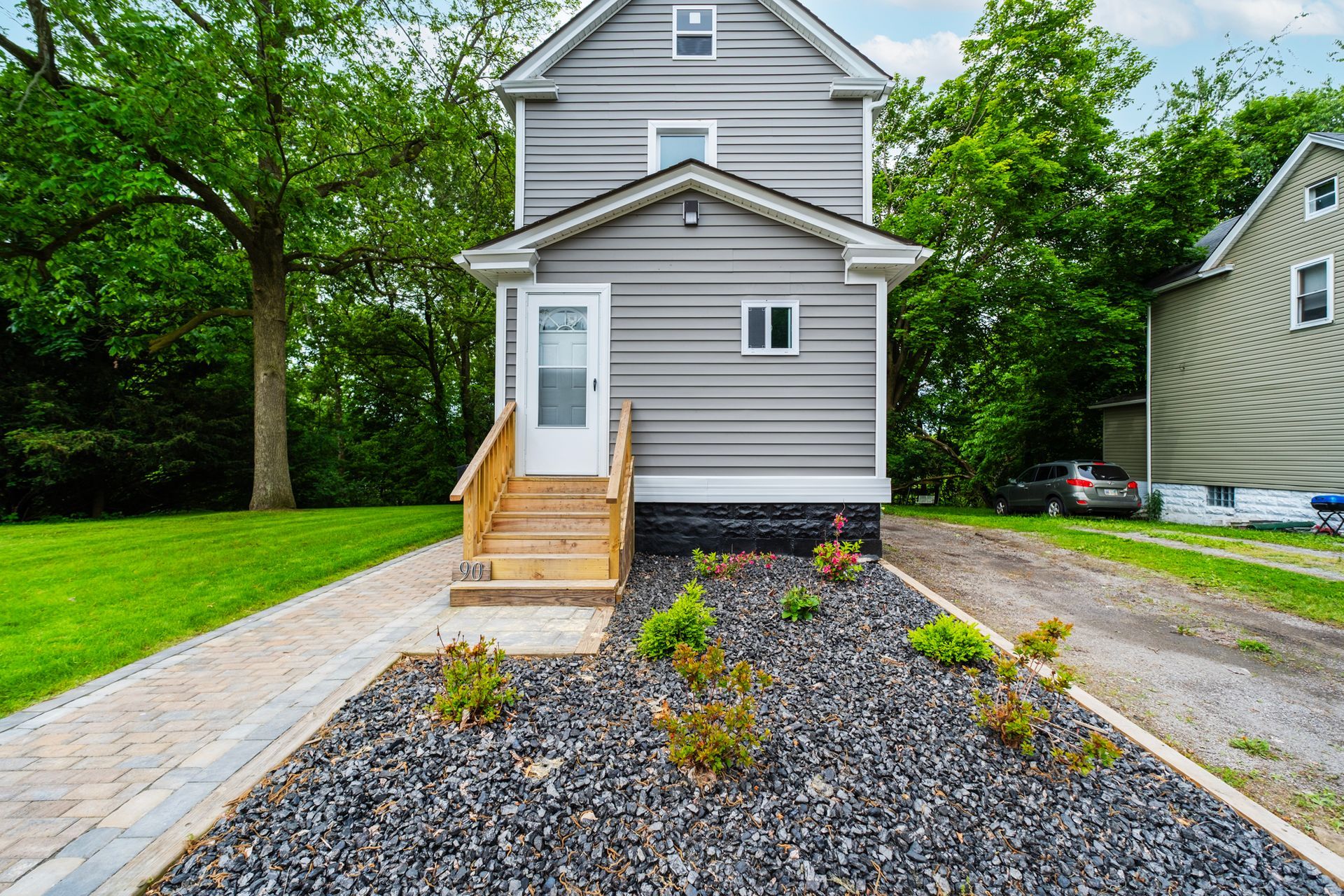 A small house with a gravel driveway in front of it.