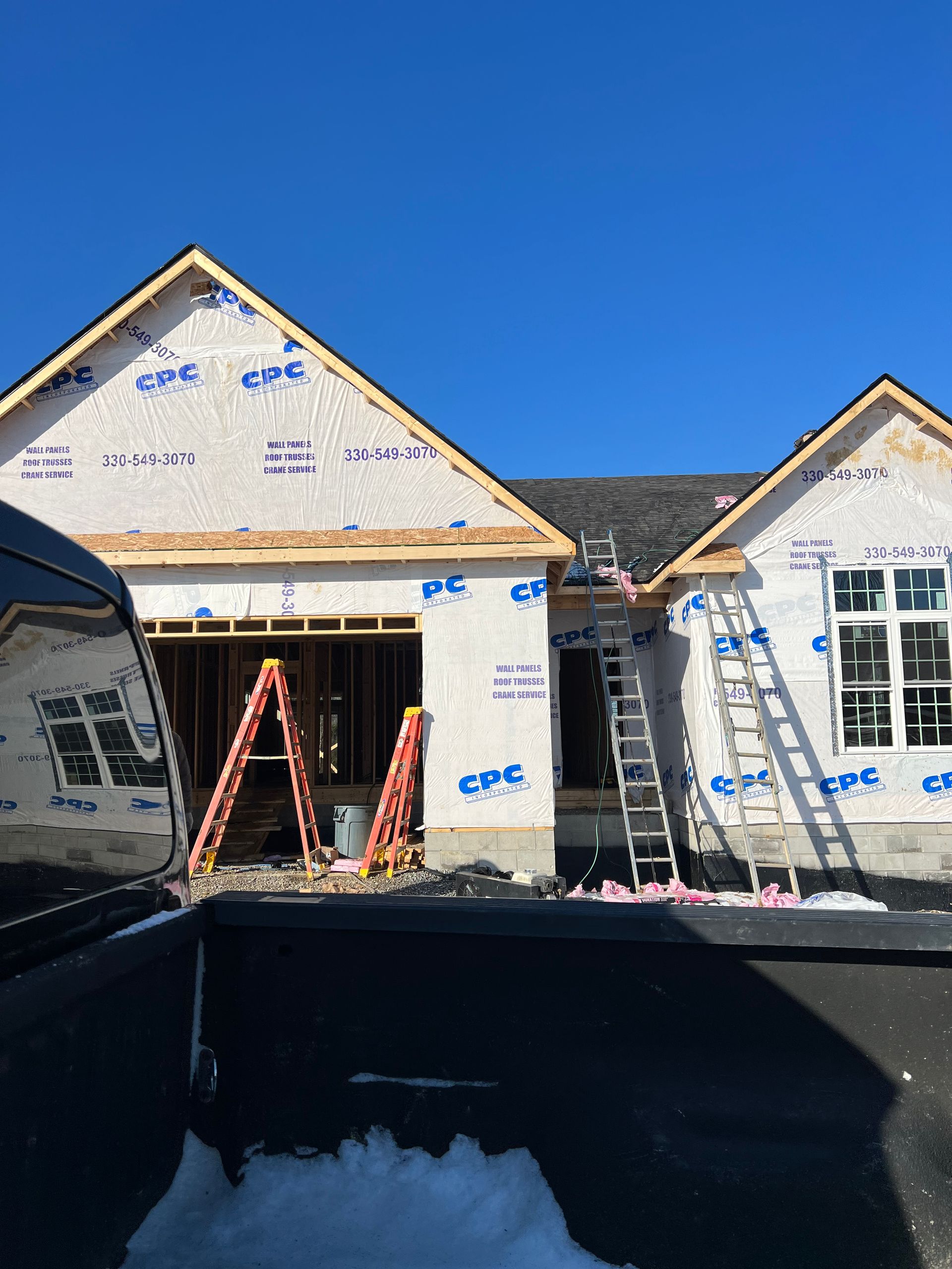 A house is being built with a truck parked in front of it.