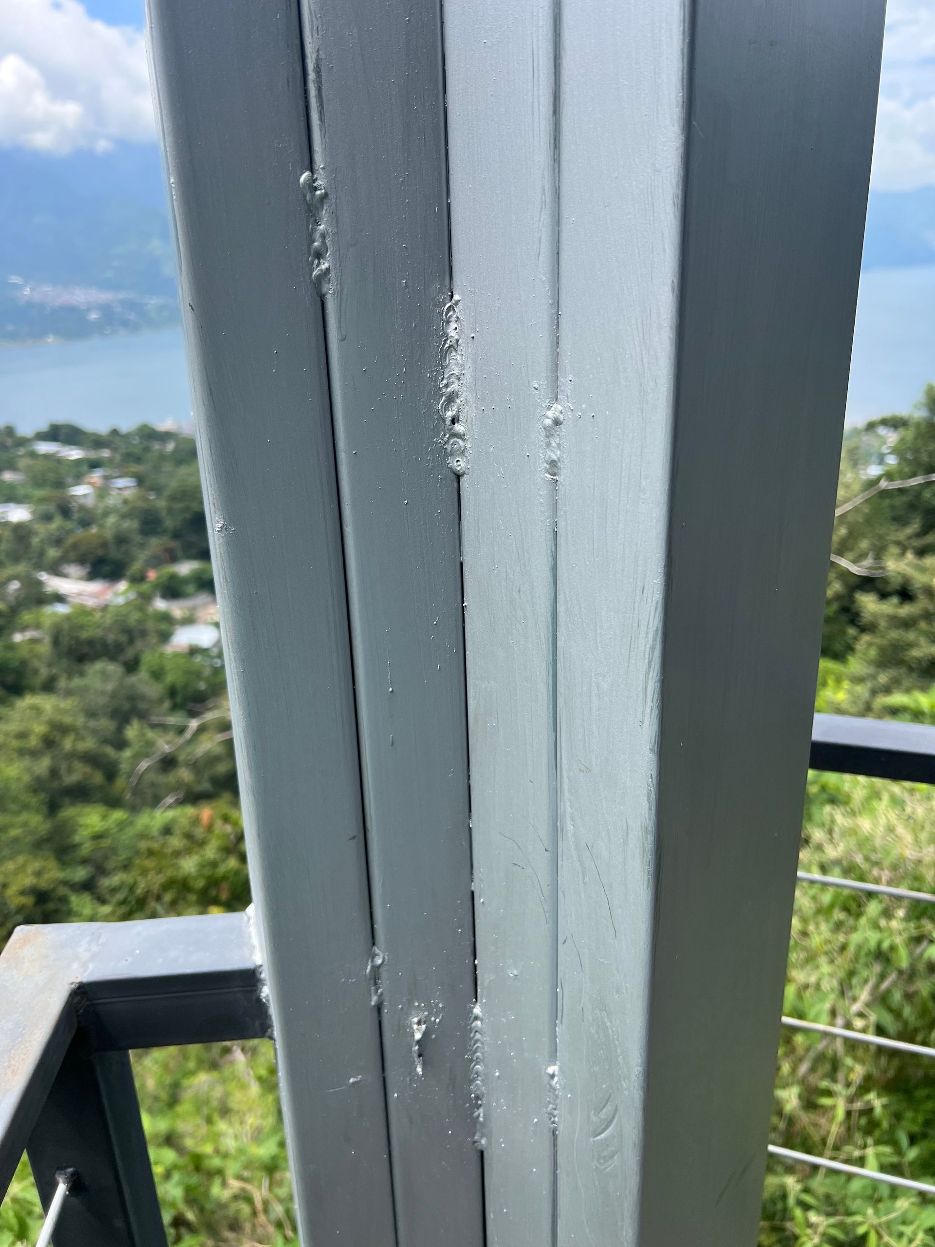 A close up of a metal pole on a balcony overlooking a body of water.
