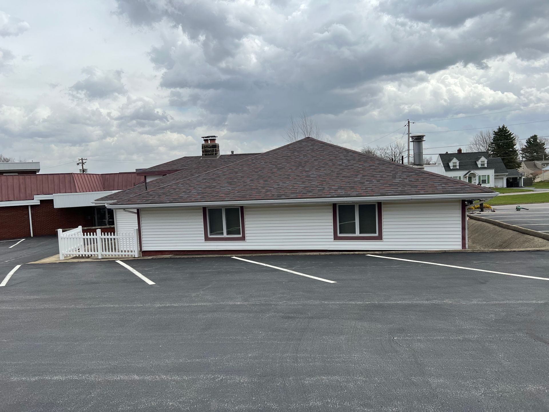 A white house with a red roof is sitting in a parking lot.