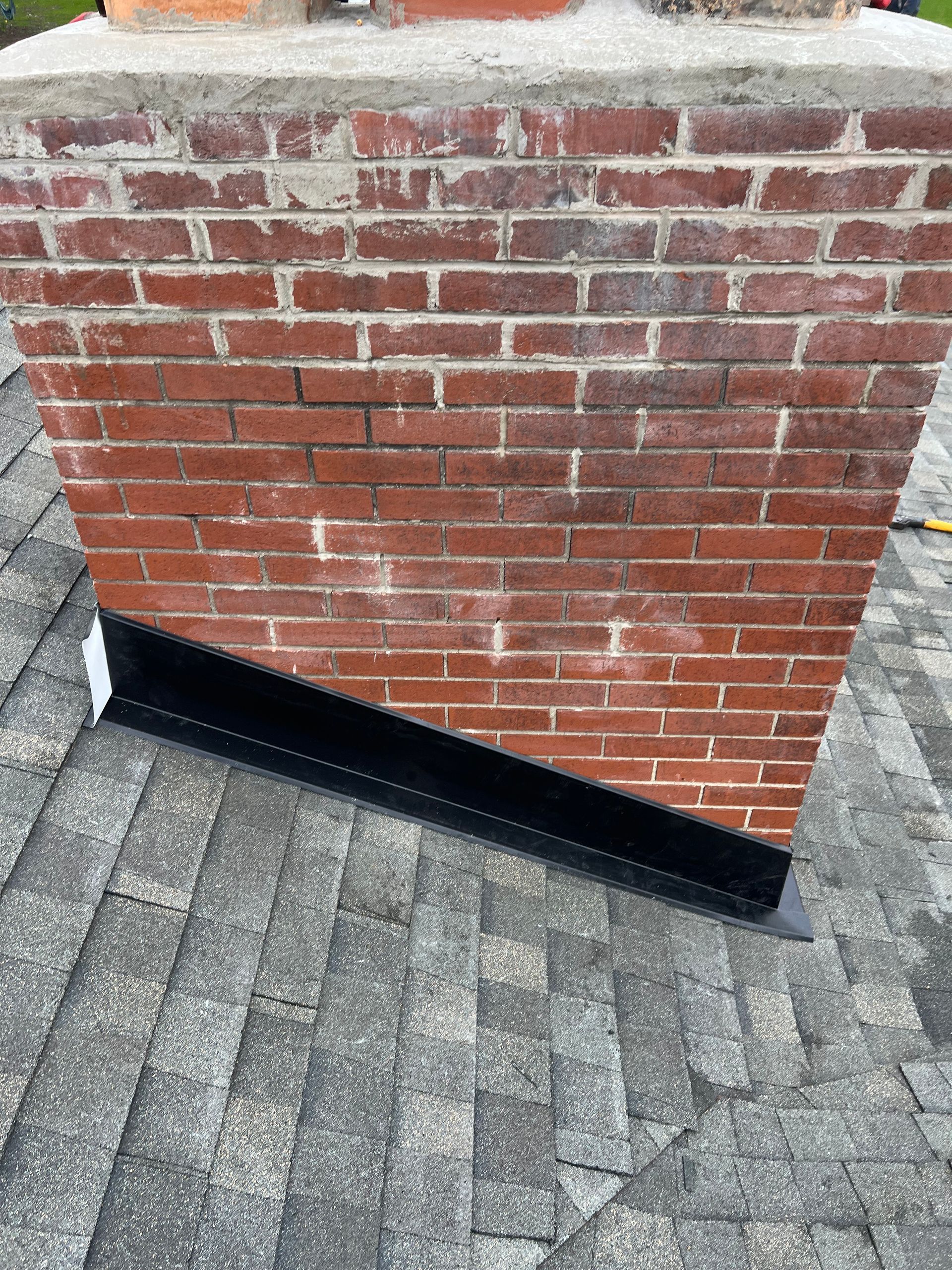 A brick chimney is sitting on top of a roof.