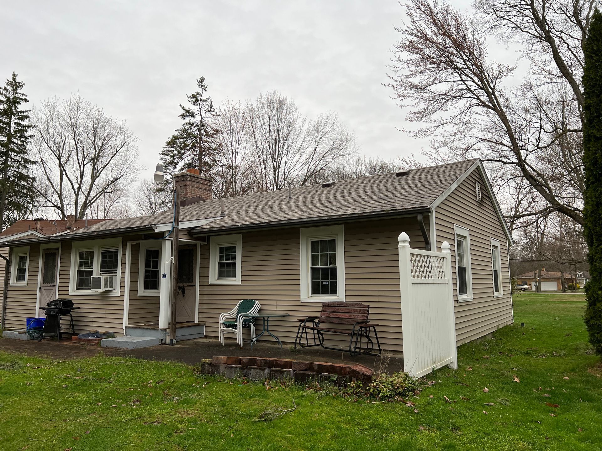 A small house with a porch and a white fence in front of it.