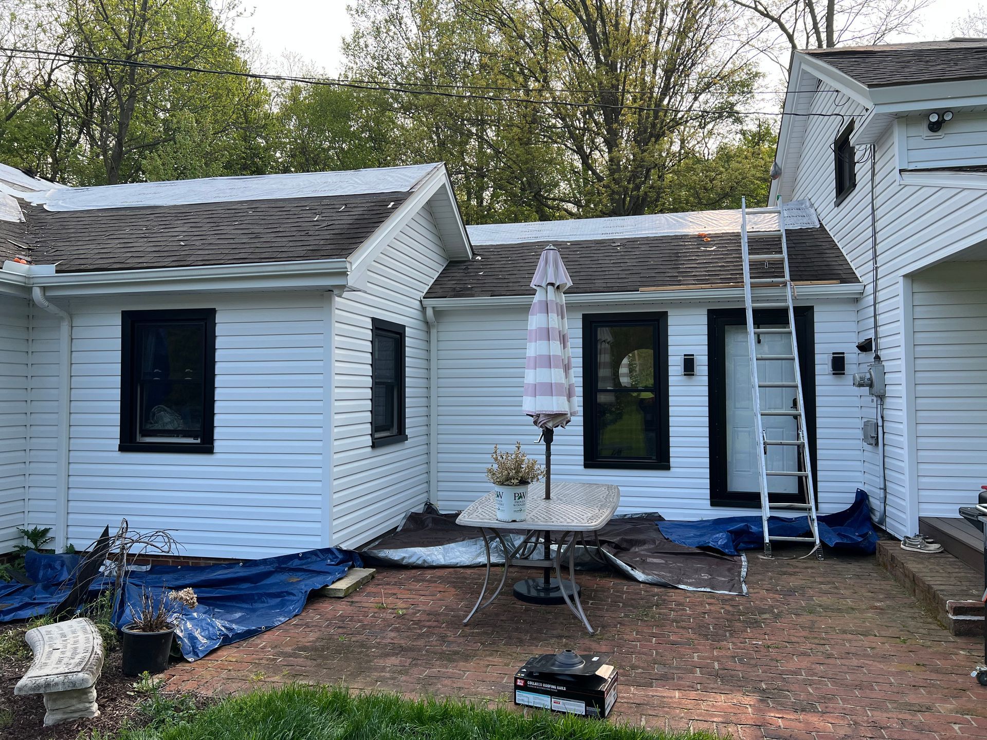 A white house with a ladder in front of it is being painted.