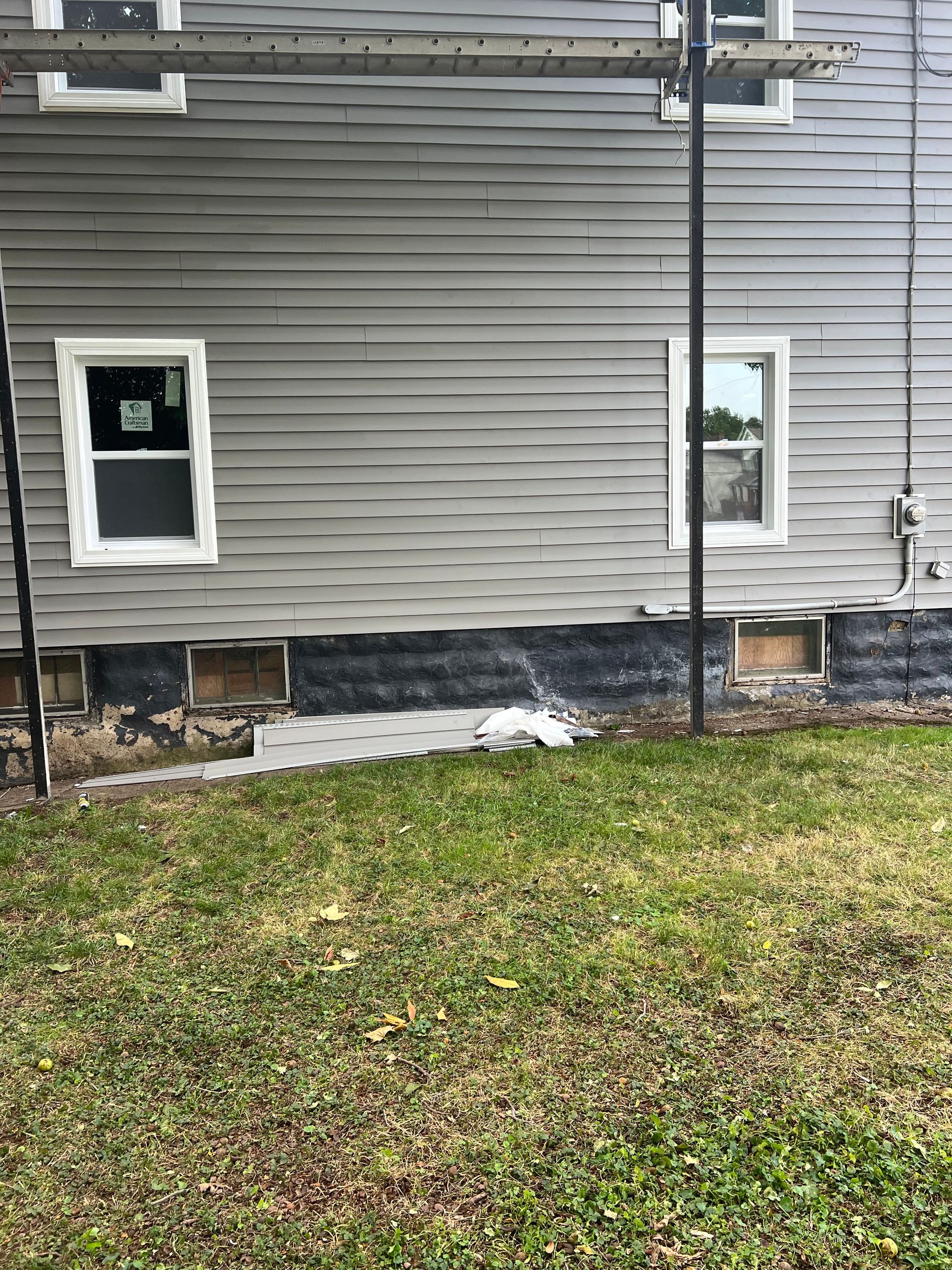 A house with a lot of windows is sitting on top of a lush green lawn.