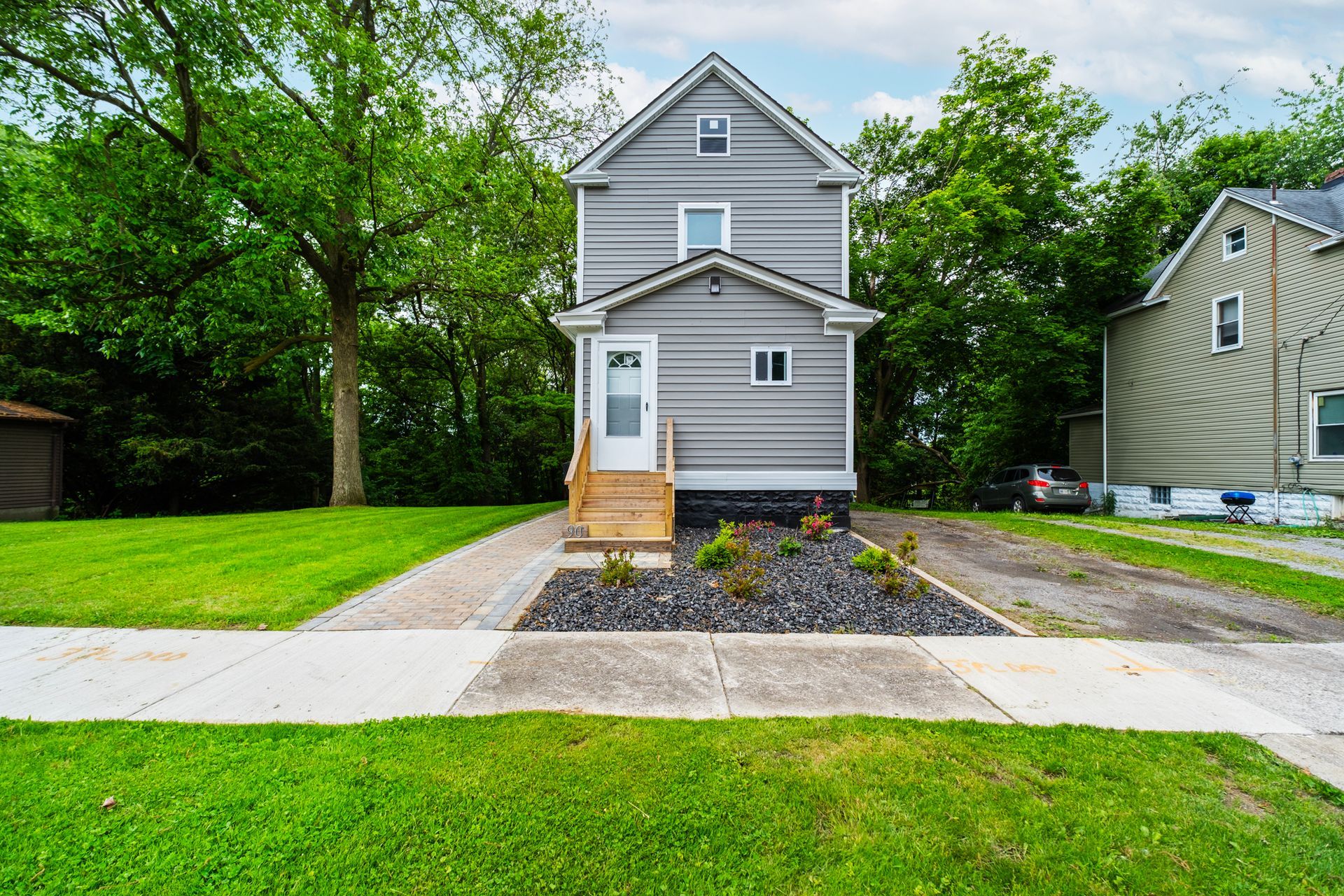 A gray house with a white door is sitting on top of a lush green lawn.