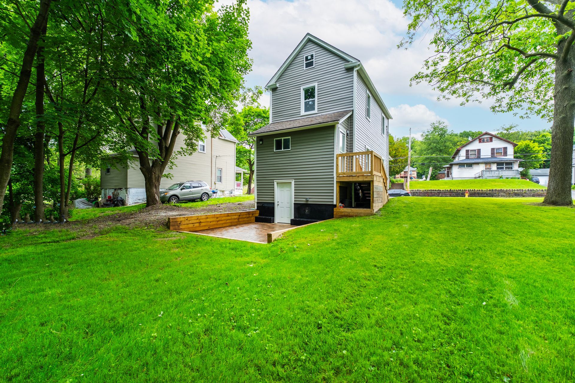 The backyard of a house with a large lawn and trees in the background.